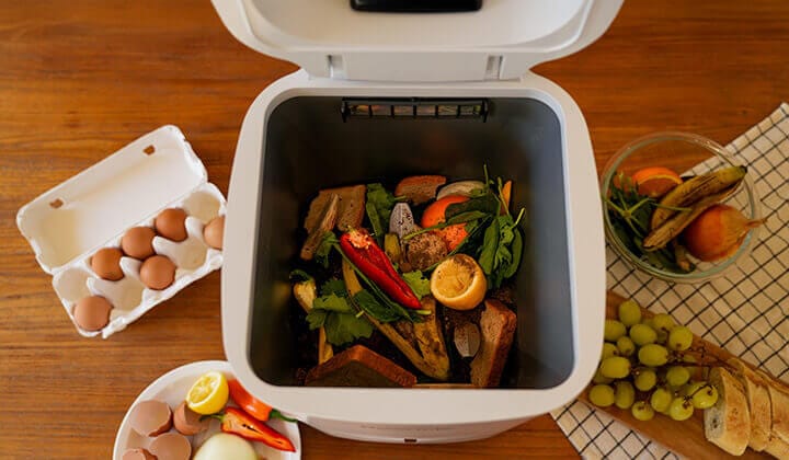 Compostador eléctrico Reencle abierto en cocina moderna con residuos orgánicos frescos