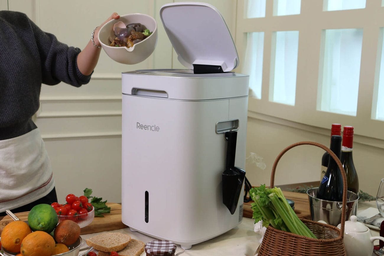 Persona incorporando residuos orgánicos de cocina en la compostera eléctrica Reencle Gravity